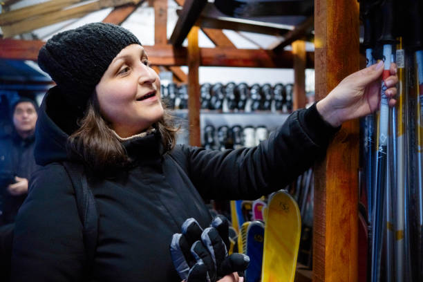 uma cliente alegre escolhe esquis em um depósito de aluguel de esqui e equipamentos de esqui. - skiing ski boot rental equipment - fotografias e filmes do acervo