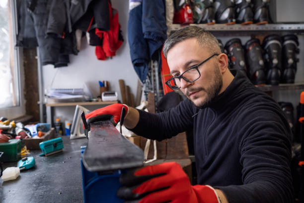 um jovem trabalhador do sexo masculino prende cuidadosamente os esquis a vises especializadas. - skiing ski boot rental equipment - fotografias e filmes do acervo