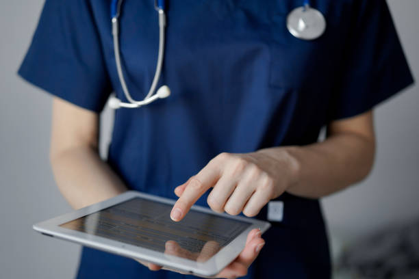 istock Doctor woman using tablet computer while standing near panorama window in clinic, close up. Physician or surgeon at work. Medicine concept 1473276886
