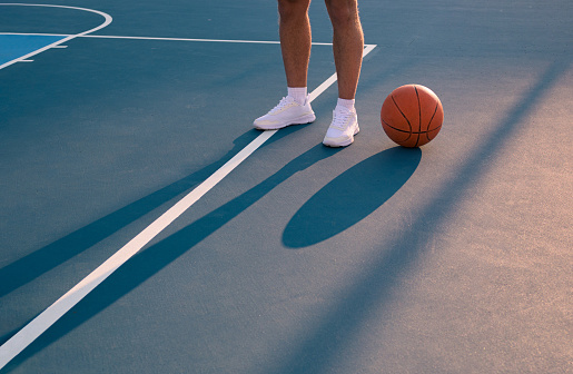 Detail of the feet of a player with a ball on a basketball court