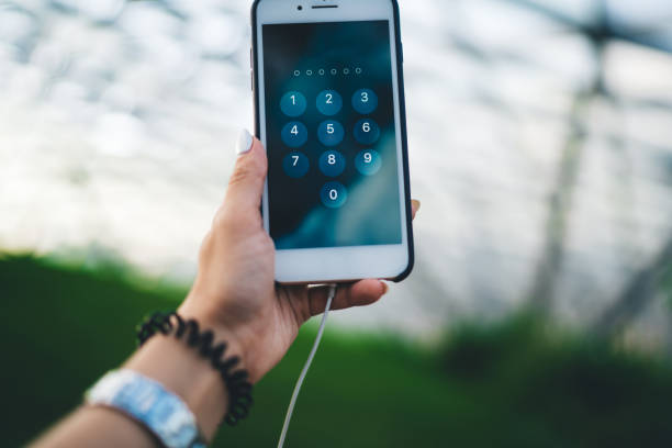 istock Cropped female blogger holding modern smartphone device open verification window for type protection password, selective focus on digital cellular technology with numbers on screen for safe using 1473282560