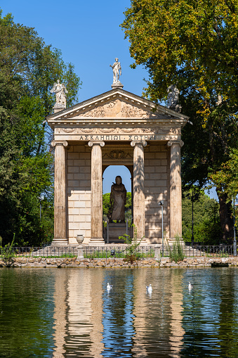 The Temple of Aesculapius in city of Rome, Italy, 18th century Classical style landmark by the lake in the gardens of the Villa Borghese.