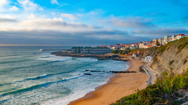 istock Aerial view - touristic coastline on summer while sunset. Beautiful seashore with skyline, waves and blue sky. Drone view over sandy beach  touristic city Ericeira , Portugal. 1473284472