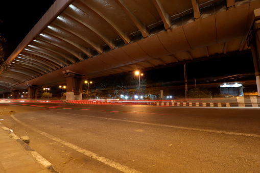 Car light travelling at night on the road under bridge