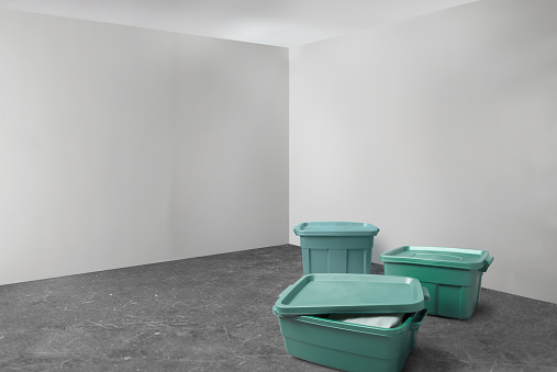 Group of green plastic storage totes in a basement