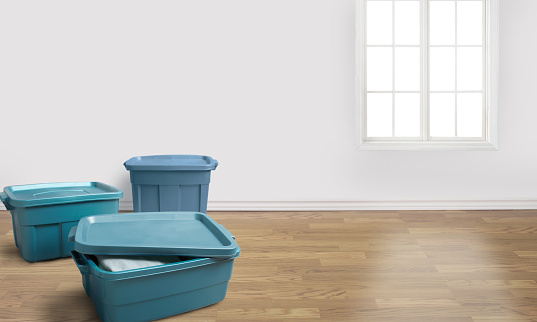Group of blue plastic storage totes in a room with a panelled wall