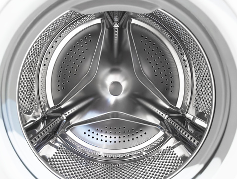 Washing machine drum close up. Washing machine background. Inside the washing machine. Metal washing machine drum. Perforated shiny metal