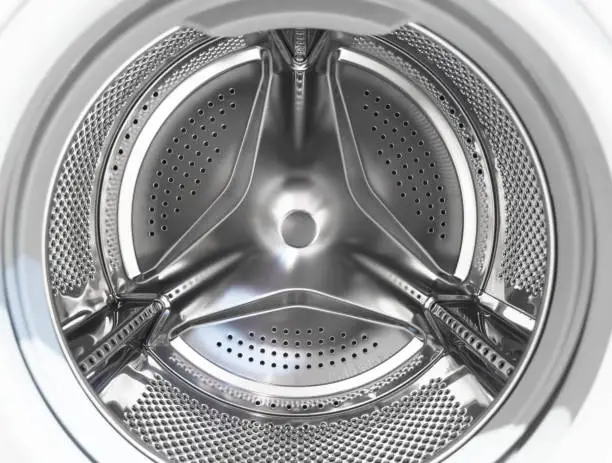 Photo of Washing machine drum close up. Washing machine background. Inside the washing machine. Metal washing machine drum. Perforated shiny metal