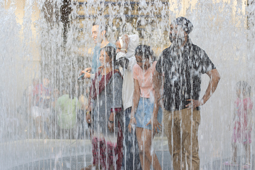 New York, NY, USA - July 2, 2022: Blurred image of visitors to the Rockefeller Center in New York City having their pictures taken while surrounded by spray fountains on a summer day.