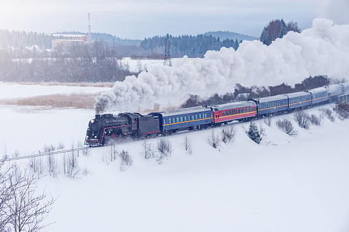Retro steam train moves at winter sunset.