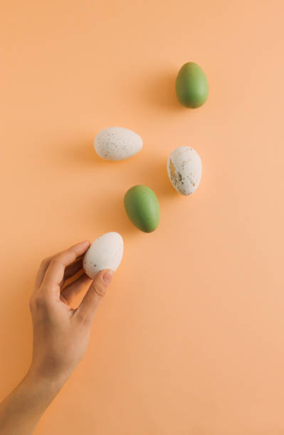 istock Easter pattern made of white and green eggs and woman's hand on pastel orange background. Minimal Easter holiday composition. Creative food concept. Top view, flat lay. 1473302499