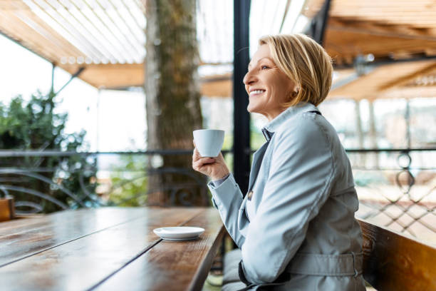 istock Smiling mid adult woman drinking coffee alone 1473304482