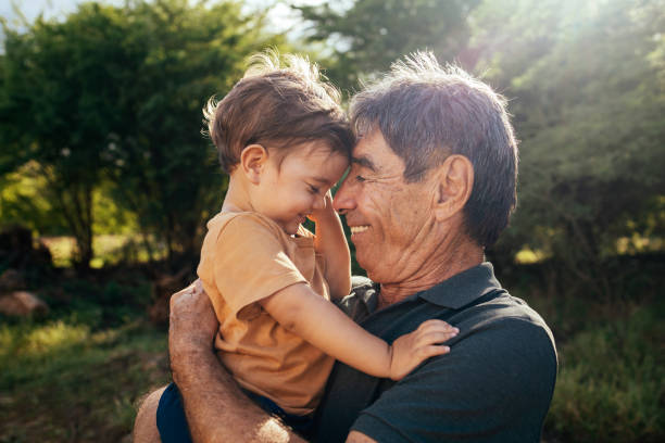 playful grandfather spending time with his grandson in park on sunny day - carinhoso imagens e fotografias de stock