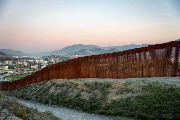 International Border Wall Between Tecate California and Tecate Mexico Near Tijuana Baja California Norte at Dusk Under Stunning Sunset with View of the City From the USA International Border Wall Between Tecate California and Tecate Mexico Near Tijuana Baja California Norte at Dusk Under Stunning Sunset with View of the City From the USA, Aerial View of the International Border Between Mexico and The USA, Drone View of the International Border Between Mexico and The United States national border stock pictures, royalty-free photos & images