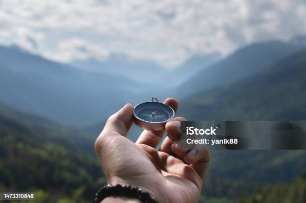 Magnetic Compass In The Palm Of A Male Hand Against The Backdrop Of A Mountain Range In The Clouds In The Summer Outdoors Travel Firstperson View Stock Photo - Download Image Now