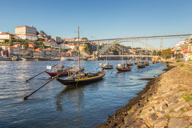 Rabelo boats moored on the Douro River, with the city of Porto and the D. Luís bridge in the background, on a summer afternoon. stock photo