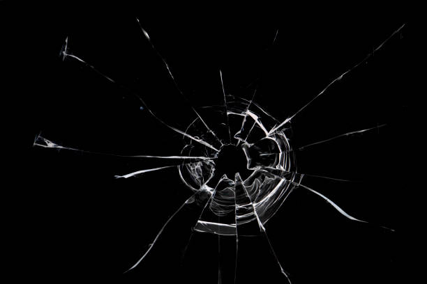istock Broken hole in glass black background 1473314685