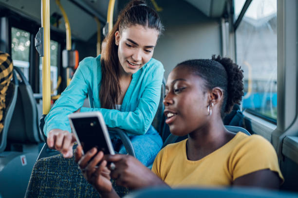 istock Multiracial female friends using a smartphone while riding a bus in the city 1473315326