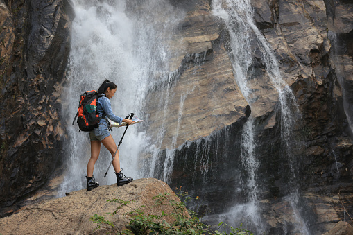 Female Tourists trekking  in forest and amazing MaeTia waterfall located in Chiangmai of Thailand . Adventure trekking in tropical rainforest. Hiking nature trail. Summer Vacation concept