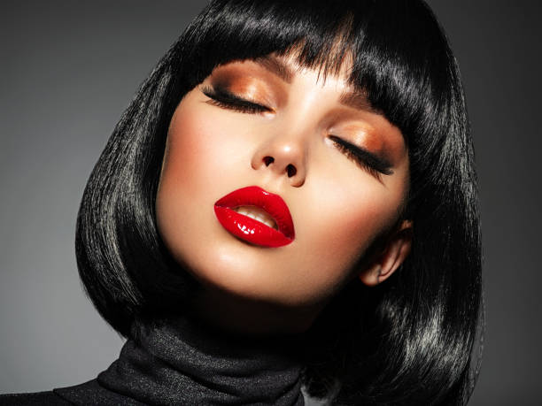 Beautiful brunette girl with red lips and black bob hairstyle. Pretty young woman with closed eyes. Closeup portrait of a model with bright makeup on a face. Fashion portrait of a pretty lady. stock photo