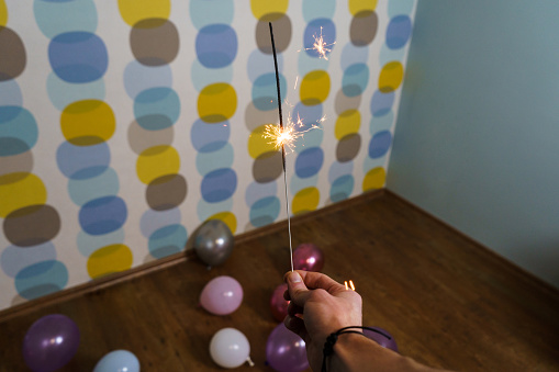 Young Man Holding a Sparkler with Balloons in the Background