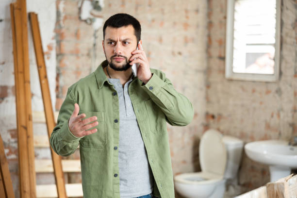 istock Dissatisfied bearded man talking on phone in house during renovation 1473319928
