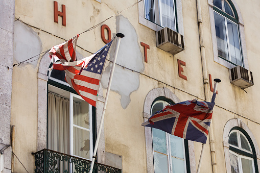 decayed old hotel facade with torn US and United Kingdom flags in front