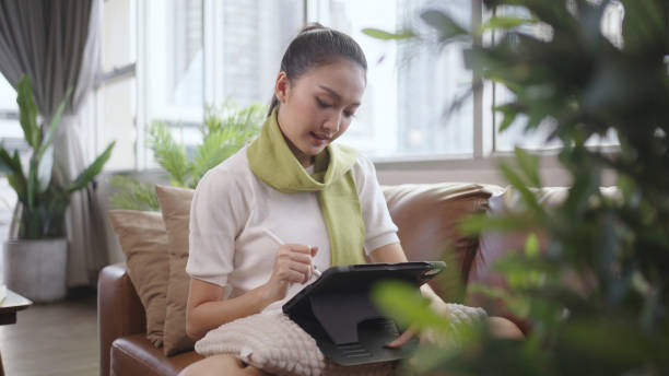Asian woman using tablet to work at home.