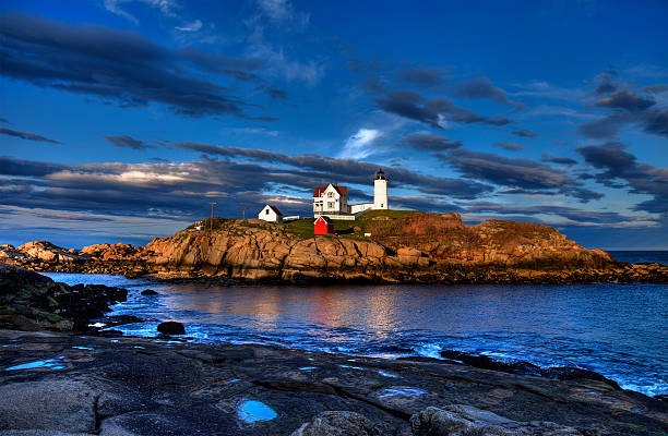 Nubble Lighthouse Sunset - High Dynamic Range The Nubble Lighthouse is one of the most photographed lighthouses in America, yet this HDR version of the nubble is truly unique thanks to the beautiful colors and sky that this evening provided. lighthouse lighting equipment reflection rock stock pictures, royalty-free photos & images