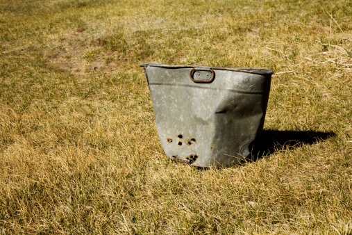 bucket with bullet holes in field