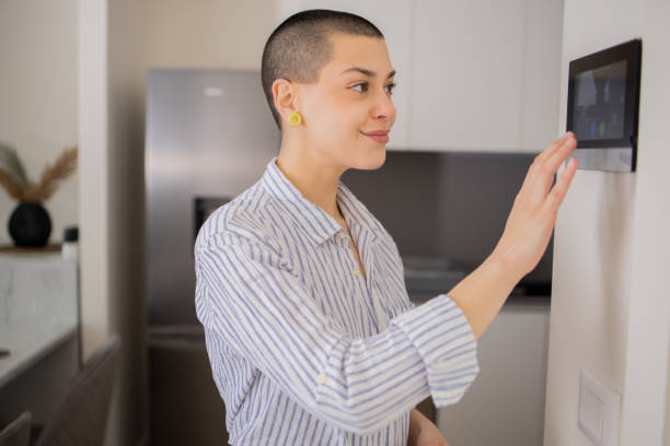 istock Young woman adjusts the temperature at home with a device on the wall 1473323906
