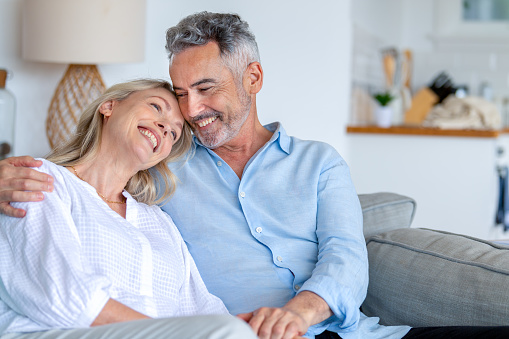 Mature couple embracing on the sofa. They are both smiling and happy and relaxed