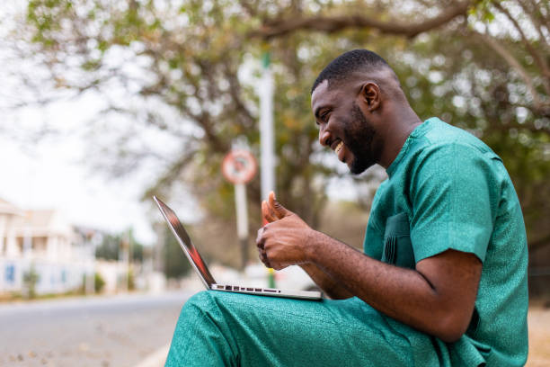 istock Young Black African Man with Laptop Computer doing video call outdoors. 1473328837