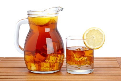 Ice tea pitcher and glasss with lemon and icecubes on wooden background