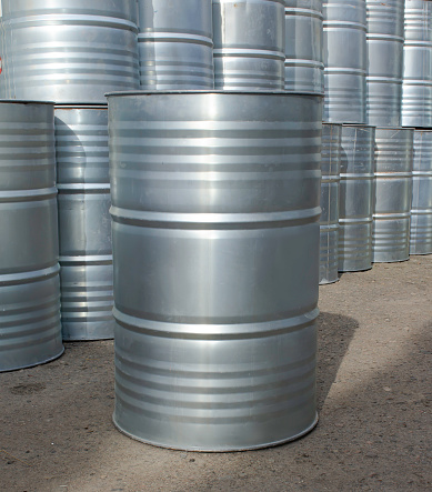 metal barrels for petroleum products, one in the front, and many barrels in the background