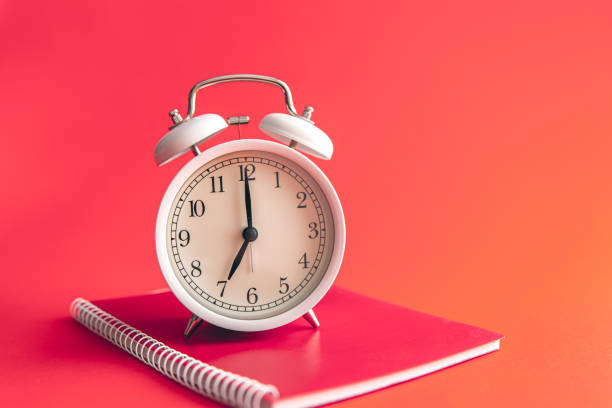 istock White alarm clock and notebook on Viva Magenta background. 1473332946