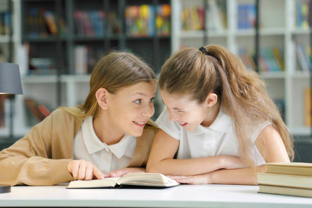 istock Girls reading book and laughing 1473336077