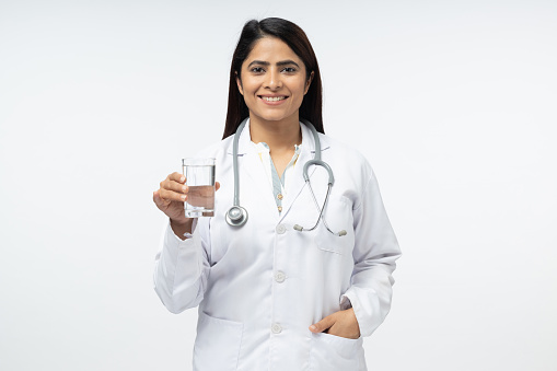 Female doctor holding glass of water, smiling, portrait