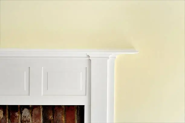 White painted fireplace with red brick against yellow wall