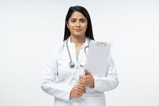 Cheerful female doctor in white uniform holding clipboard