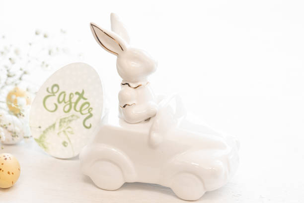istock Easter background with a ceramic hare in the car and eggs on a white background, 1473338201