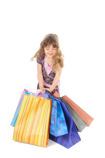 Adorable happy little girl with a large stack of heavy shopping bags