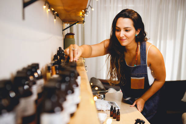 parfumeuse brésilienne travaillant dans son atelier, choisissant des huiles essentielles - huiles essentielles conservation photos et images de collection