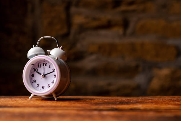 istock Alarm clock on wooden table on dark background. Place for text. 1473350486