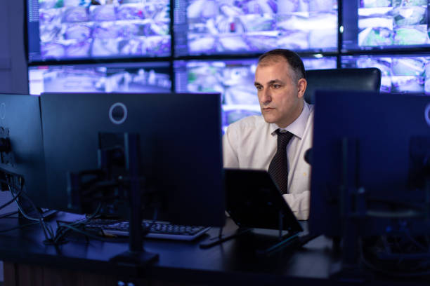 istock Man working in surveillance room and looking at monitors 1473350941