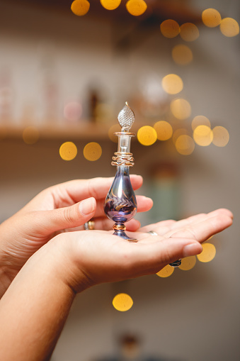 Close up shot of an anonymous woman holding a bottle of perfume.