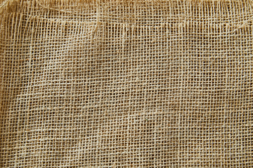 A beautiful light burlap natural texture background, with shades and shadows, background ideal for product placement, with a large copy space area