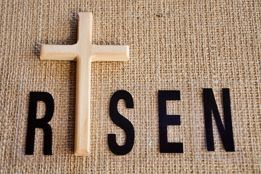 A wooden religious cross with the word RISEN for a religion or easter background.