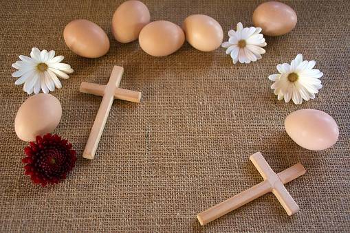 An easter background of eggs with  a wood cross and flowers.