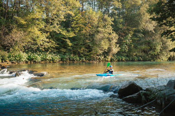 istock Man cruising down whitewater rapids in a kayak 1473373444